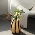 Vase with flowers next to sofa