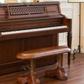 Bench with shoe-shaped feet in front of piano