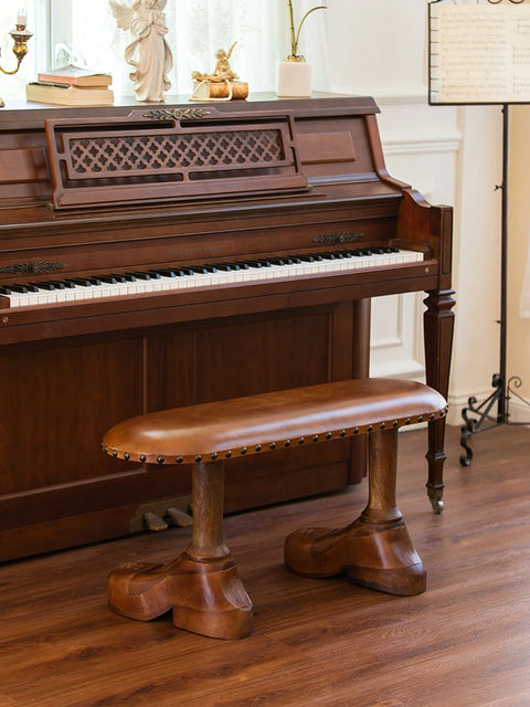 Bench with shoe-shaped feet in front of piano