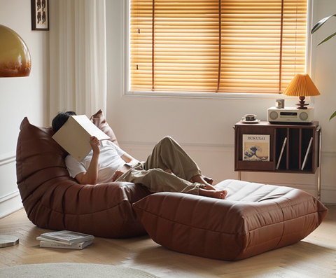 Leather-look slouch couch chair with matching foot stool.