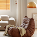 Leather-look slouch couch chair with blanket.