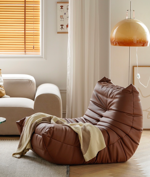 Leather-look slouch couch chair with blanket.